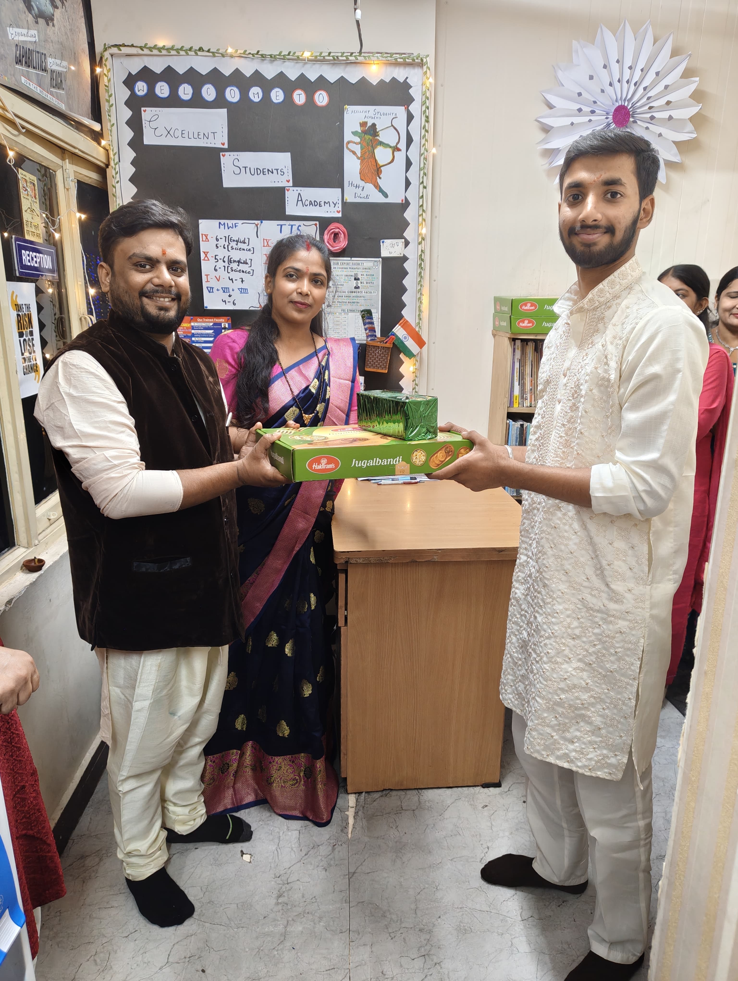 Founder hands sweet box to young alumni