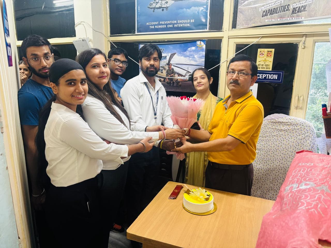 Faculty celebrating a birthday with flowers and cake
